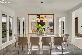 Curated furniture packages - Modern dining room with a glass table and chairs, featuring a chandelier and large windows.